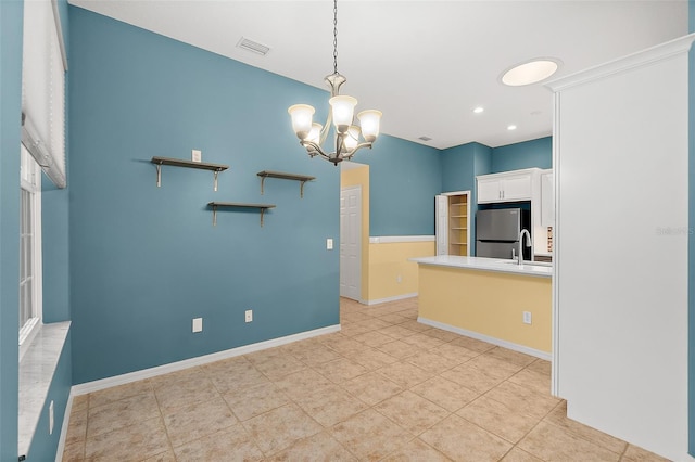 kitchen with stainless steel fridge, sink, pendant lighting, a chandelier, and white cabinetry