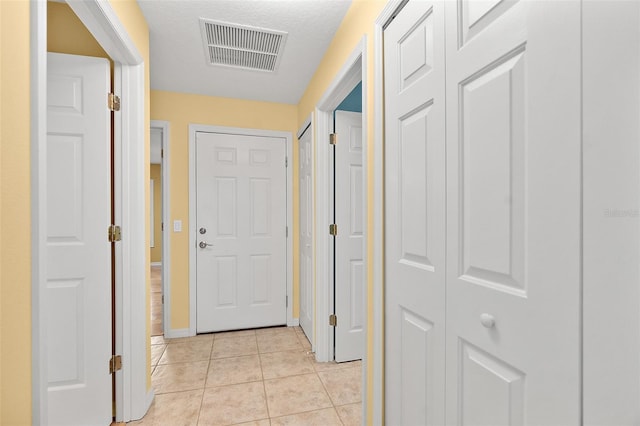 corridor with light tile patterned floors and a textured ceiling