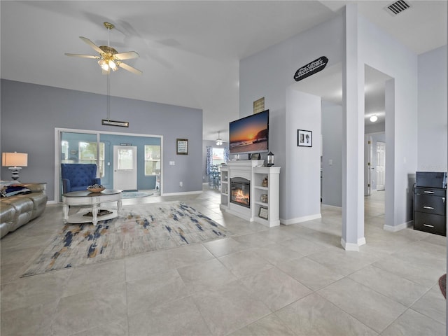 tiled living room with ceiling fan and a high ceiling