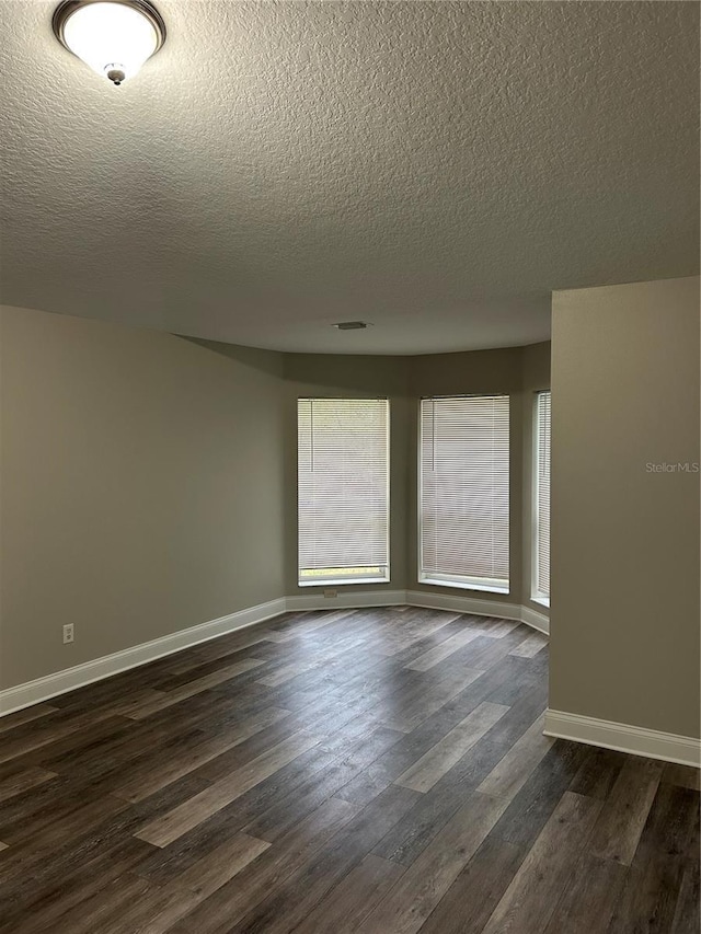 spare room with a textured ceiling and dark wood-type flooring