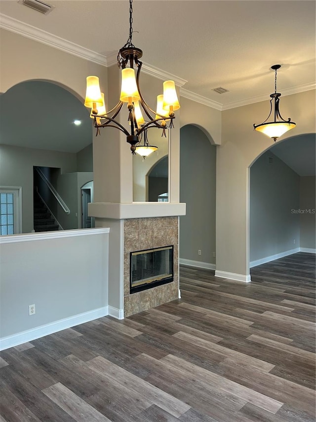 unfurnished living room featuring a tile fireplace, dark hardwood / wood-style flooring, and ornamental molding