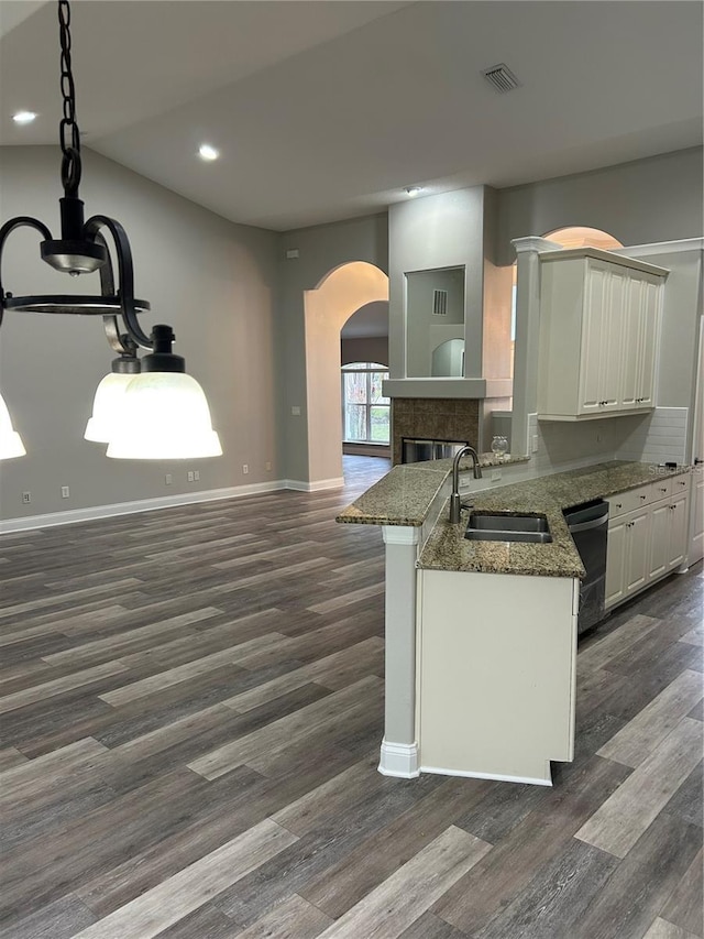 kitchen featuring dishwasher, sink, dark hardwood / wood-style floors, kitchen peninsula, and decorative light fixtures