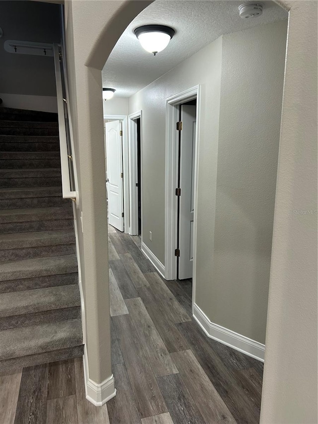 hallway with dark hardwood / wood-style flooring and a textured ceiling