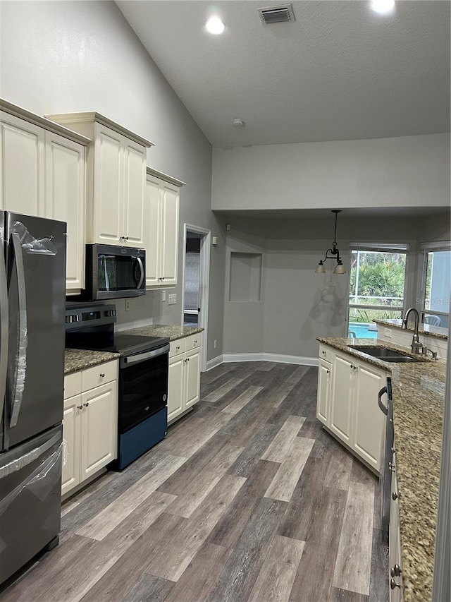 kitchen with black range with electric stovetop, sink, stainless steel fridge, wood-type flooring, and vaulted ceiling