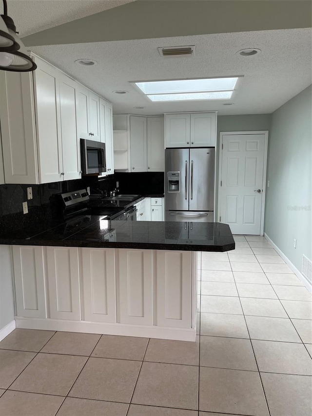 kitchen featuring kitchen peninsula, white cabinetry, light tile patterned floors, and stainless steel appliances