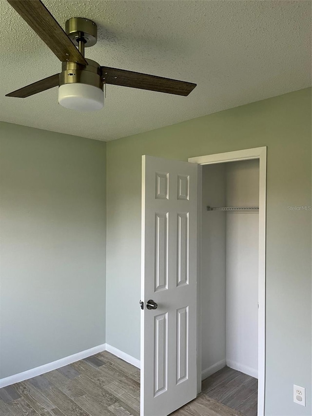 unfurnished bedroom featuring a textured ceiling, a closet, dark wood-type flooring, and ceiling fan