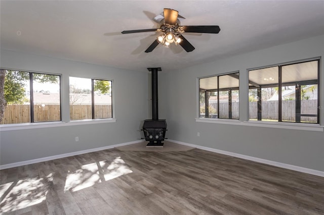 unfurnished living room with a healthy amount of sunlight, hardwood / wood-style floors, and a wood stove