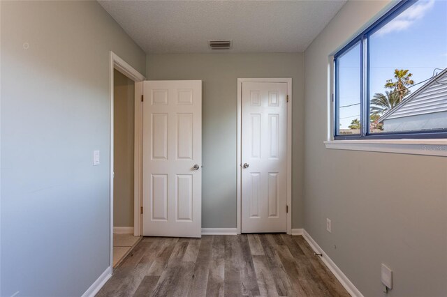 unfurnished bedroom featuring hardwood / wood-style floors and a textured ceiling