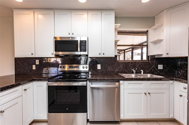 kitchen featuring dark stone countertops, sink, stainless steel appliances, and white cabinets