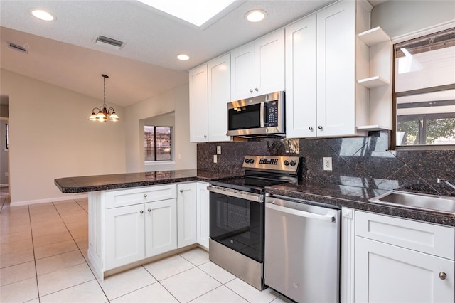 kitchen featuring appliances with stainless steel finishes, decorative light fixtures, kitchen peninsula, and white cabinets