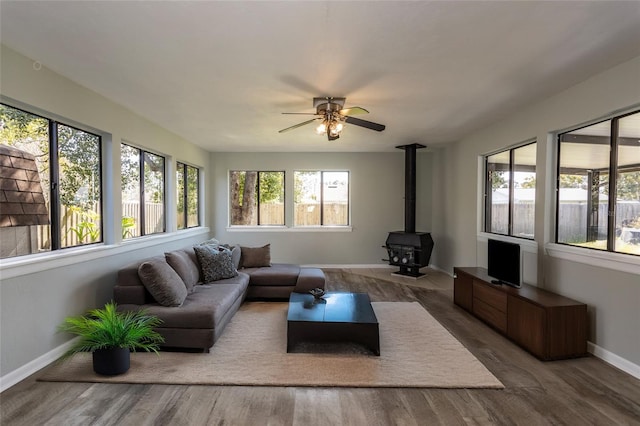 sunroom with ceiling fan and a wood stove