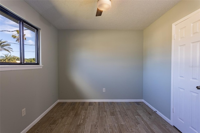 empty room with ceiling fan, dark hardwood / wood-style floors, and a textured ceiling