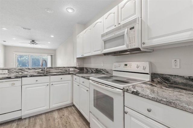 kitchen with a textured ceiling, dark stone countertops, light hardwood / wood-style flooring, white appliances, and white cabinets