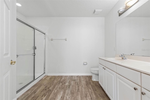 bathroom with an enclosed shower, vanity, wood-type flooring, a textured ceiling, and toilet