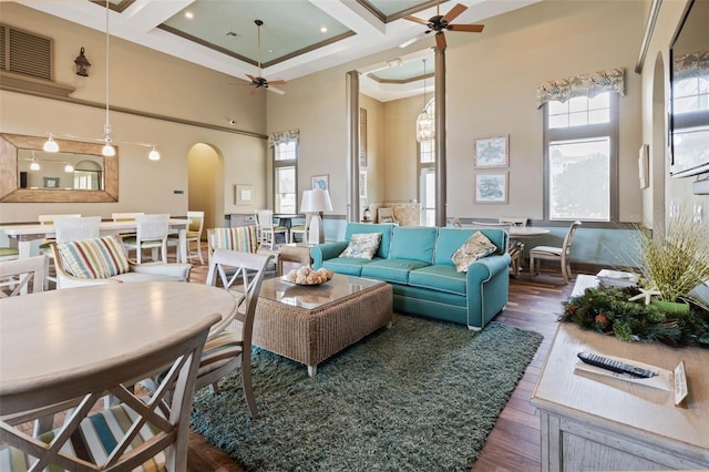 living room featuring coffered ceiling, ceiling fan, a healthy amount of sunlight, and a high ceiling