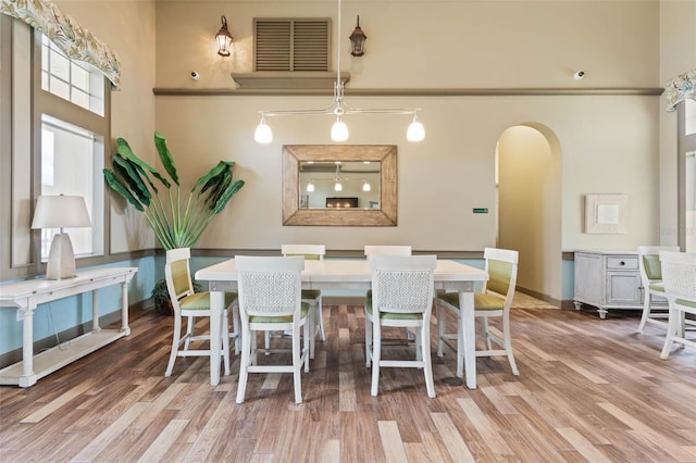 dining space with a towering ceiling and wood-type flooring