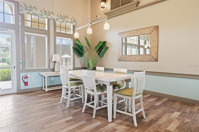 dining room with hardwood / wood-style flooring and a towering ceiling