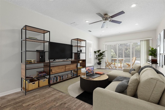 living room featuring ceiling fan, hardwood / wood-style floors, and a textured ceiling