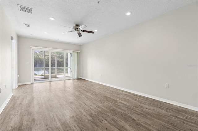 empty room with ceiling fan, hardwood / wood-style floors, and a textured ceiling