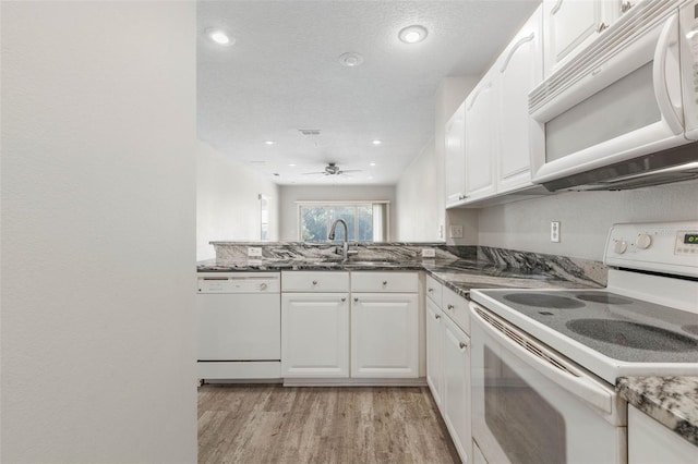 kitchen featuring white cabinetry, dark stone countertops, and white appliances