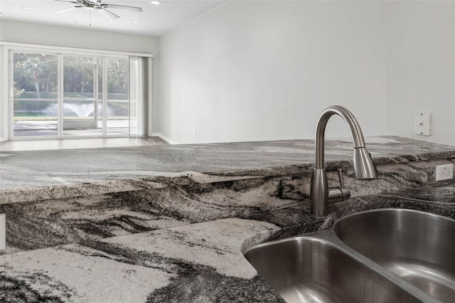 interior space with dark stone countertops, sink, and ceiling fan