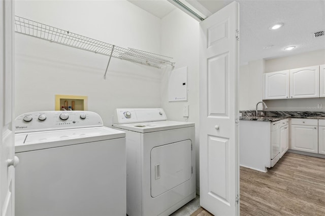 washroom with washing machine and clothes dryer, sink, and light hardwood / wood-style flooring