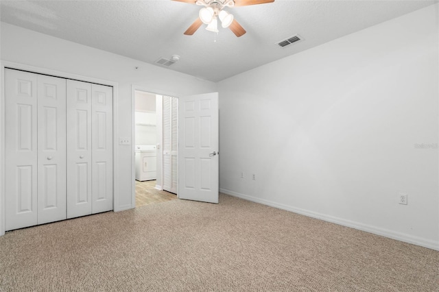 unfurnished bedroom featuring washer / dryer, light colored carpet, a textured ceiling, a closet, and ceiling fan