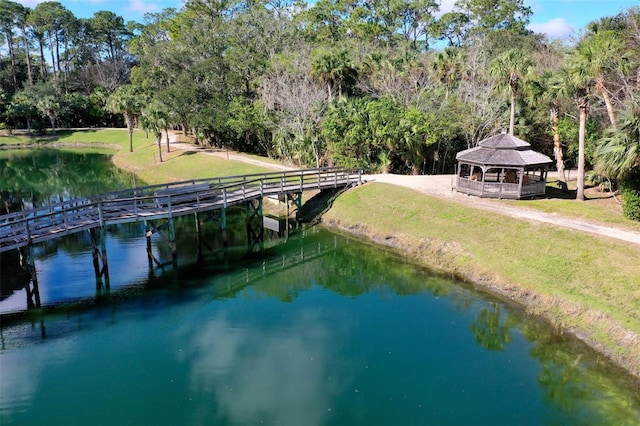 view of dock with a gazebo, a water view, and a lawn