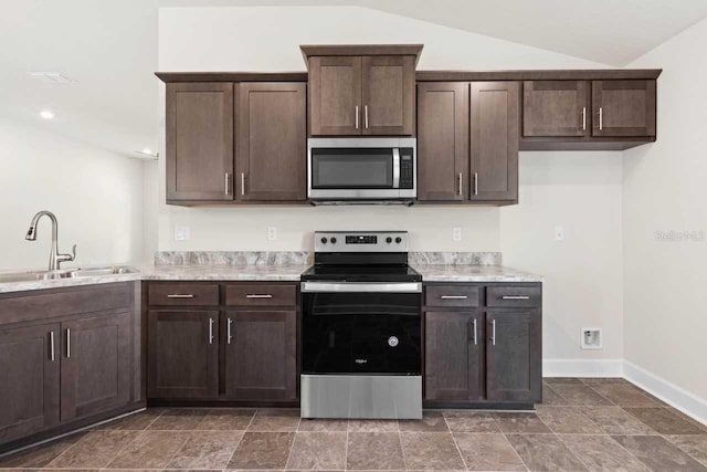 kitchen featuring lofted ceiling, sink, dark brown cabinets, and appliances with stainless steel finishes