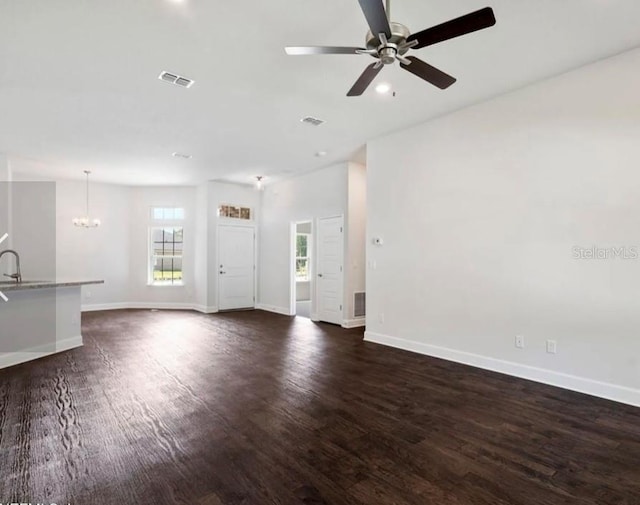 unfurnished living room with sink, ceiling fan with notable chandelier, and dark hardwood / wood-style floors