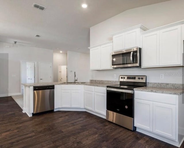 kitchen featuring sink, white cabinetry, stainless steel appliances, dark hardwood / wood-style floors, and vaulted ceiling