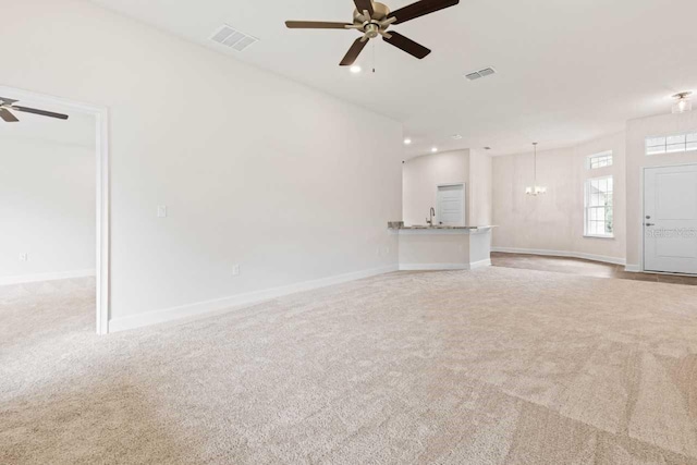 unfurnished living room with ceiling fan with notable chandelier and light colored carpet