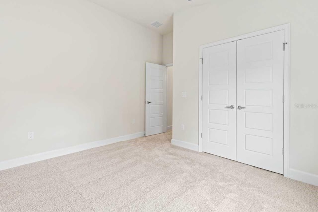 unfurnished bedroom with light carpet and a closet