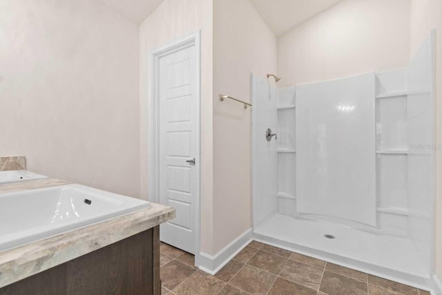 bathroom featuring vanity, lofted ceiling, and a shower