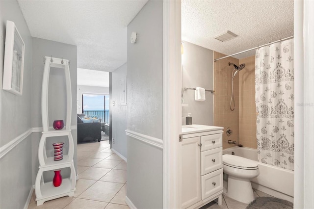 full bathroom featuring tile patterned flooring, shower / bath combination with curtain, a textured ceiling, toilet, and vanity