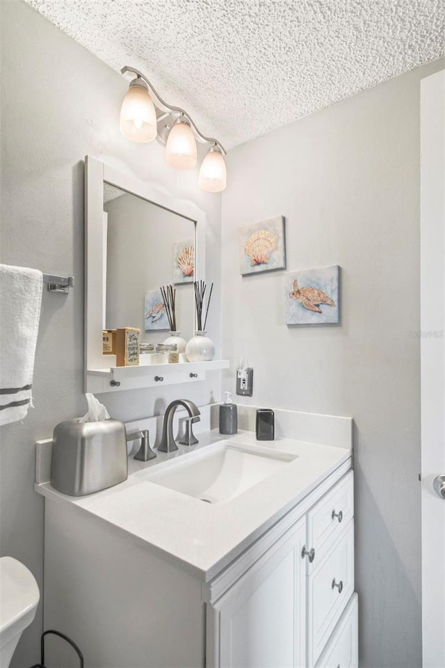 bathroom featuring vanity, a textured ceiling, and toilet