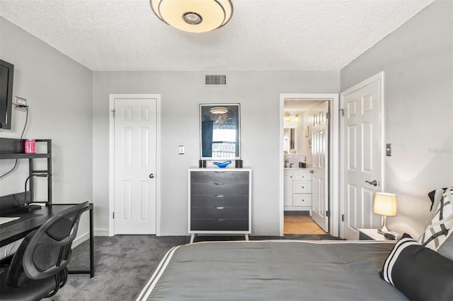 bedroom featuring carpet, a textured ceiling, and ensuite bathroom