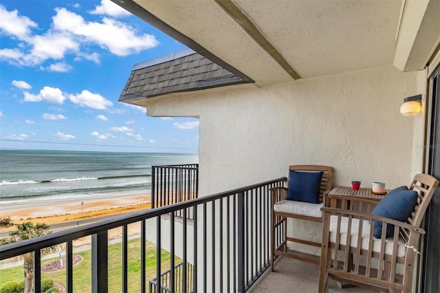 balcony with a water view and a view of the beach