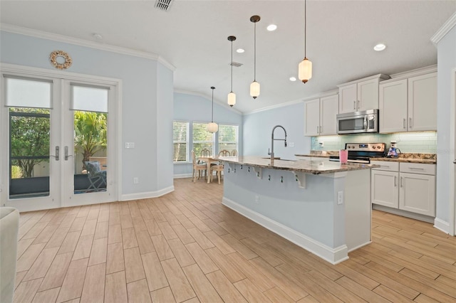 kitchen featuring backsplash, appliances with stainless steel finishes, wood tiled floor, ornamental molding, and light stone countertops