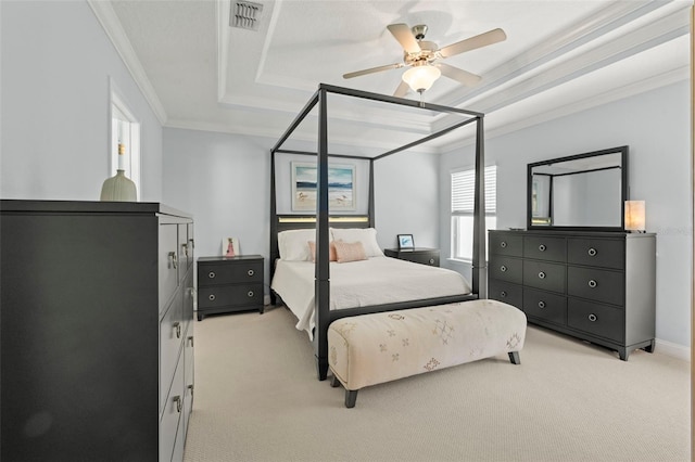 bedroom with ornamental molding, a tray ceiling, visible vents, and light colored carpet