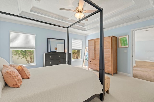 carpeted bedroom featuring visible vents, baseboards, a raised ceiling, ceiling fan, and crown molding