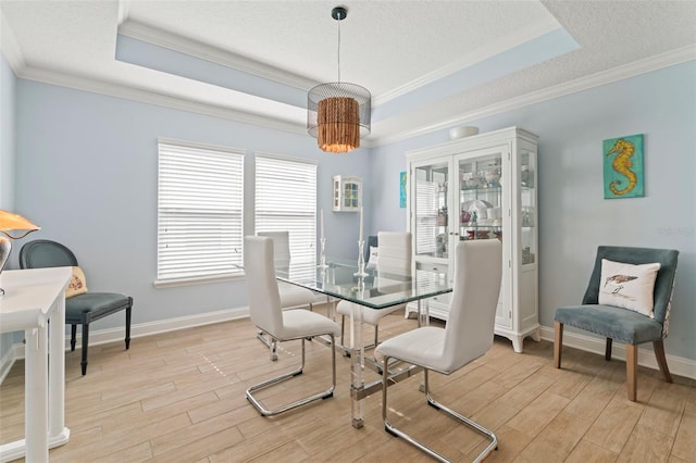 dining room featuring light wood-type flooring, a tray ceiling, and crown molding