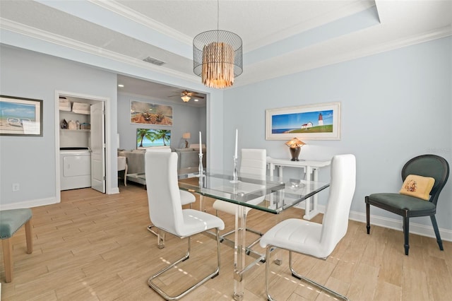 dining area featuring ornamental molding, a tray ceiling, washer / clothes dryer, and wood finished floors