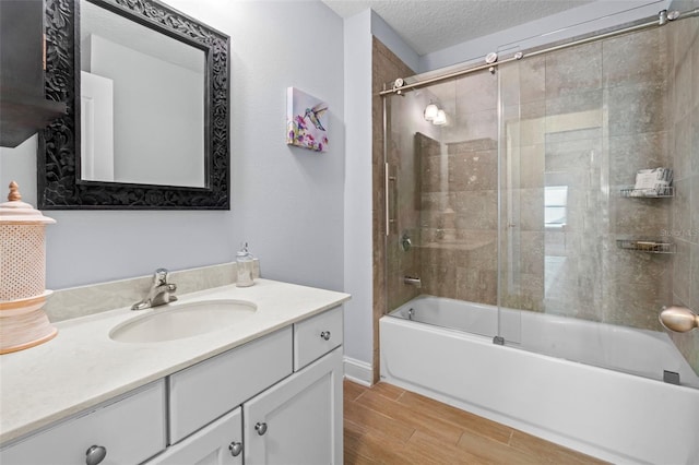 full bath featuring a textured ceiling, wood finish floors, vanity, and enclosed tub / shower combo