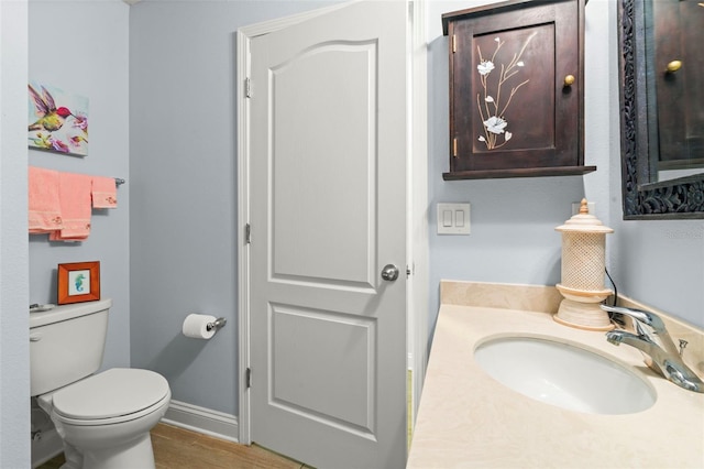 bathroom with baseboards, vanity, toilet, and wood finished floors