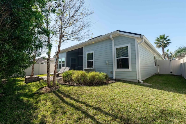 back of property with a sunroom, a fenced backyard, a gate, and a yard