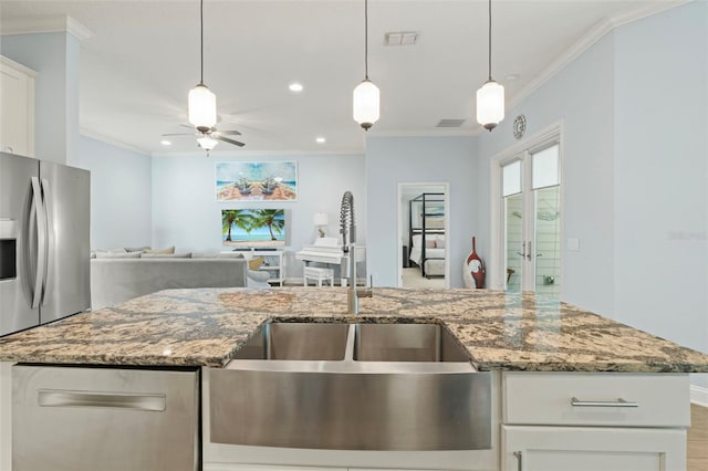 kitchen with crown molding, open floor plan, a sink, and hanging light fixtures