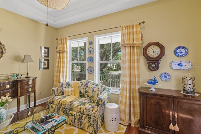 living room with hardwood / wood-style flooring, a raised ceiling, and ornamental molding