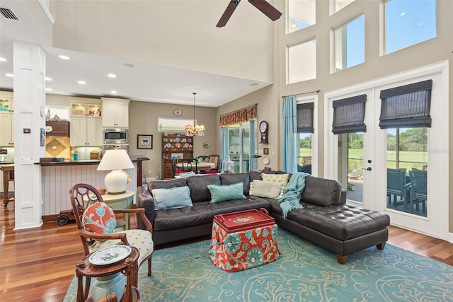 living room featuring french doors, ceiling fan with notable chandelier, hardwood / wood-style flooring, and a wealth of natural light