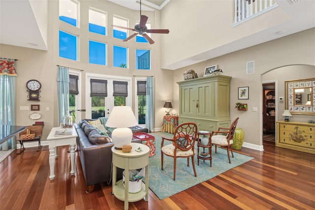 living room with a high ceiling, dark hardwood / wood-style floors, french doors, and ceiling fan